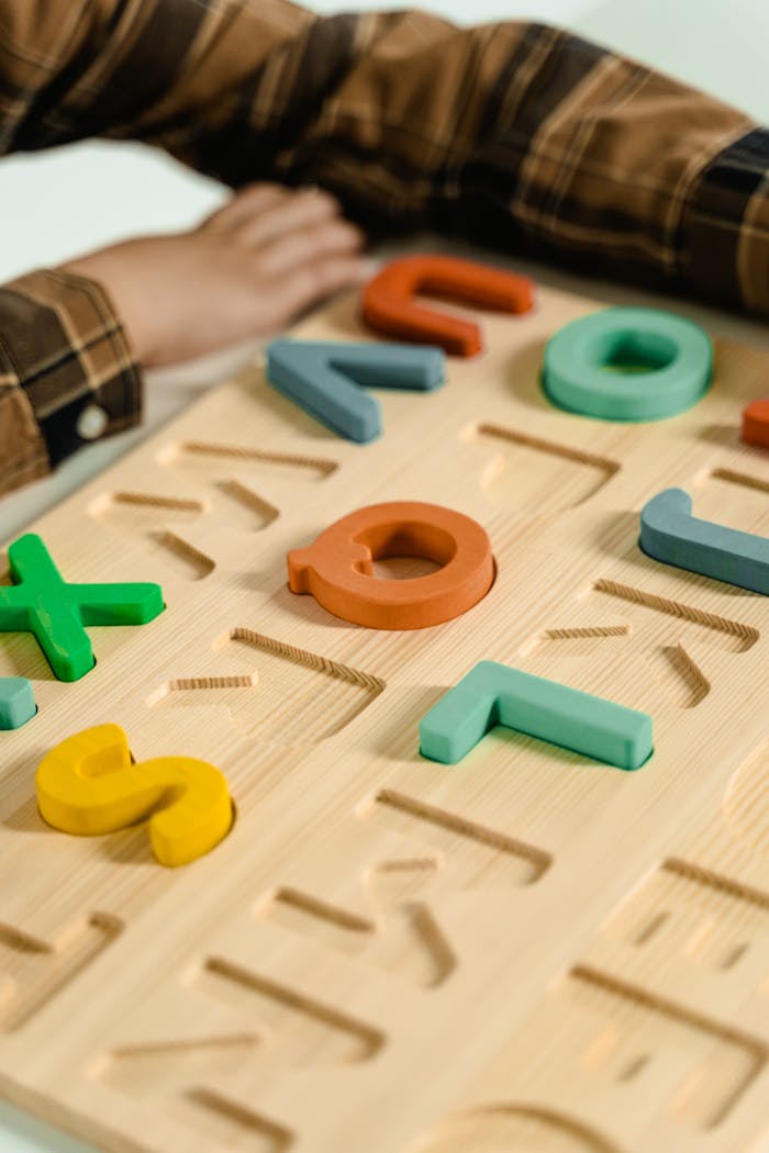 Colorful wooden letters puzzle with child's hands in focus, promoting fun learning.